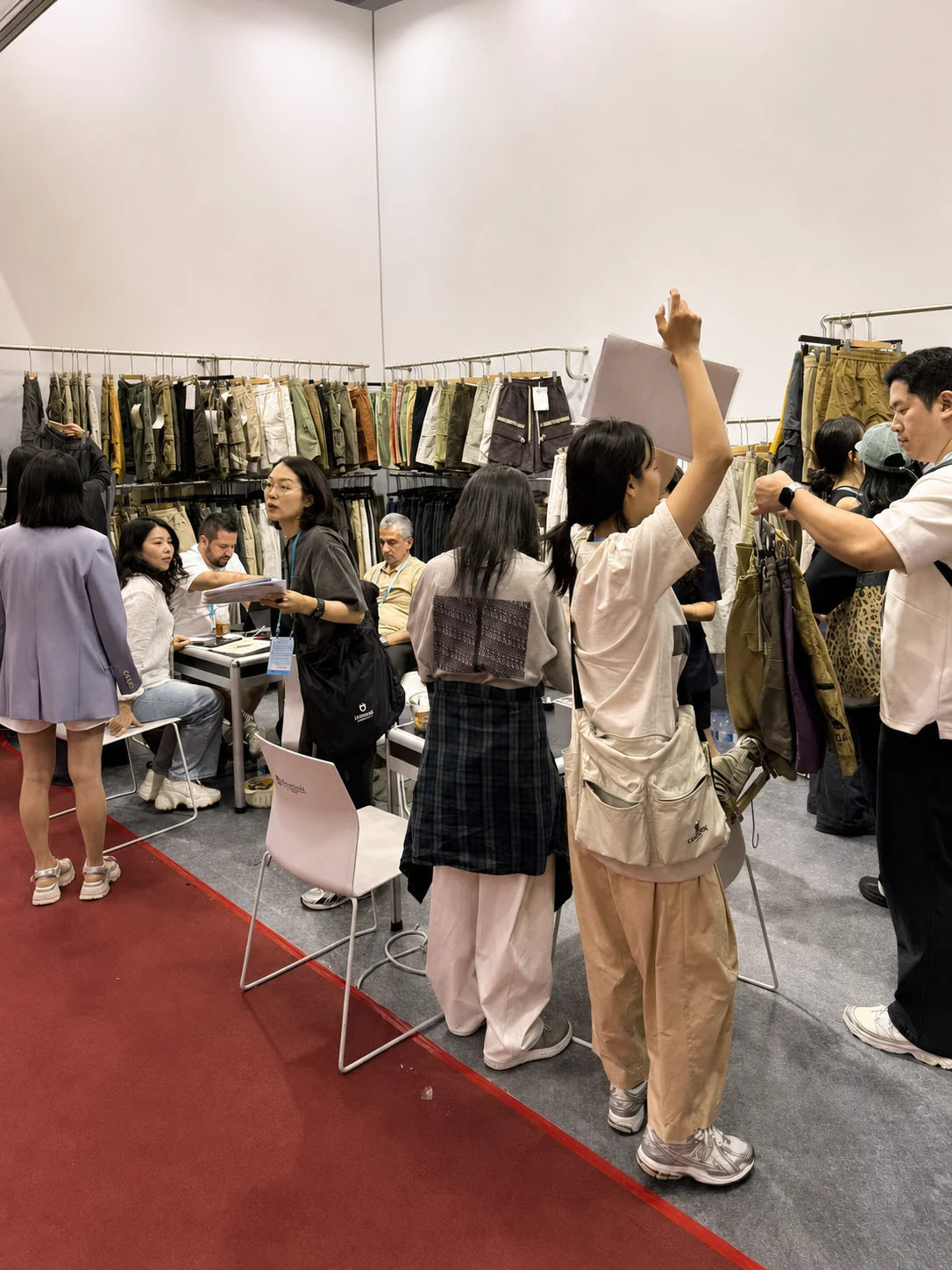 People looking at garment samples and discussing styles at an exhibition booth